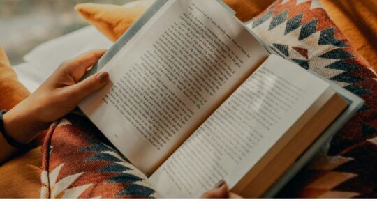 Opengeslagen boek in de handen van een vrouw.