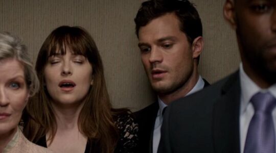 Anastasia Steele en Christian Grey in de lift met andere mensen.