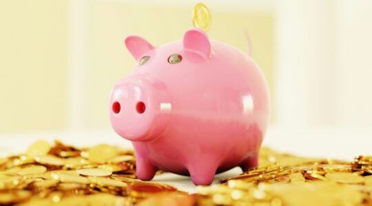 Roze spaarvarken op een hoop vol geld.