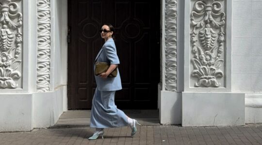 Vrouw loopt in pale blue outfit over straat.