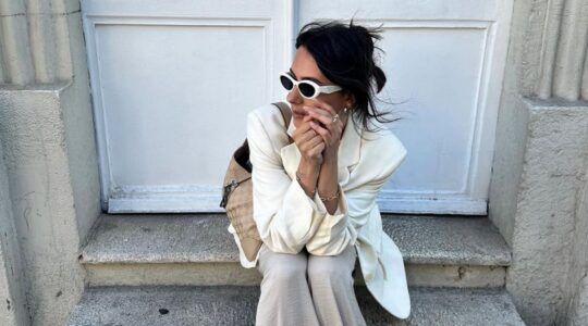 Vrouw met crèmekleurige outfit en witte zonnebril