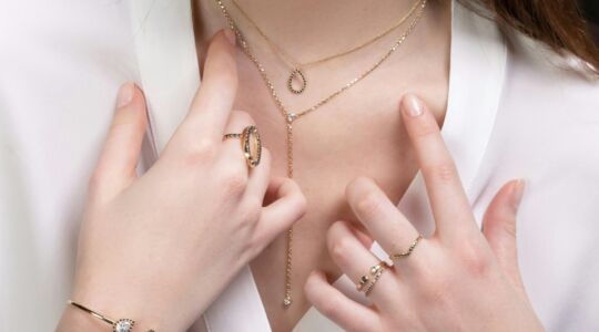 Hals en handen van een vrouw met sieraden.