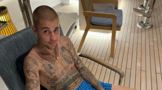 Justin Bieber op een stoel kijkend naar de camera.