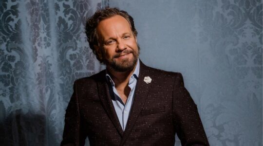 Carlo Boszhard in pak lachend naar de camera.