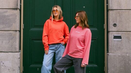 Twee modellen van Sizz the brand voor een groene deur met de nieuwe koninsdagcollectie.