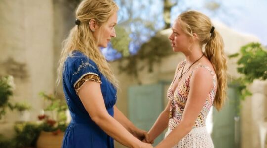 Donna en Sophie kijken elkaar aan terwijl ze elkaars handen vast in Mamma Mia.
