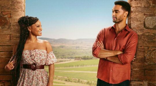 Hoofdpersonages uit You, Me & Tuscany kijken lachend naar elkaar voor een Toscaans landschap.