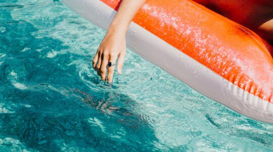 Luchtbed in het water met een hand er naast.