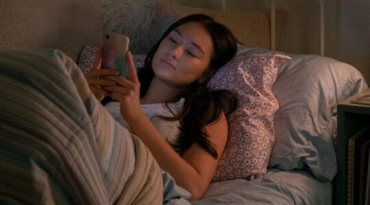 Meisje in bed op haar telefoon.