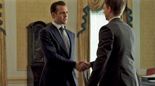 Personages uit Suits geven elkaar een hand.