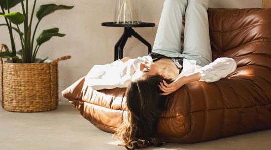 Vrouw ligt op fauteuil.