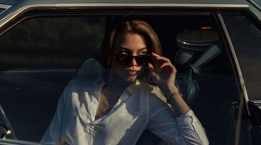 Vrouw met zonnebril in de auto.