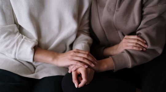 Vrouwen houden elkaars handen vast,