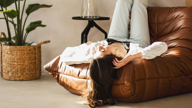 Vrouw ligt op fauteuil.