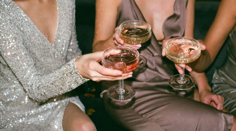 Drie vrouwen proosten met een glas champagne.