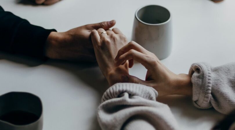man en vrouw die elkaars handen vasthouden