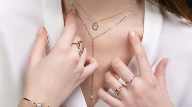 Hals en handen van een vrouw met sieraden.