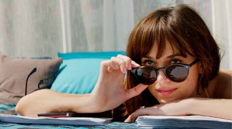 Anastasia Steele op een zonnebedje met haar zonnebril op haar neus.